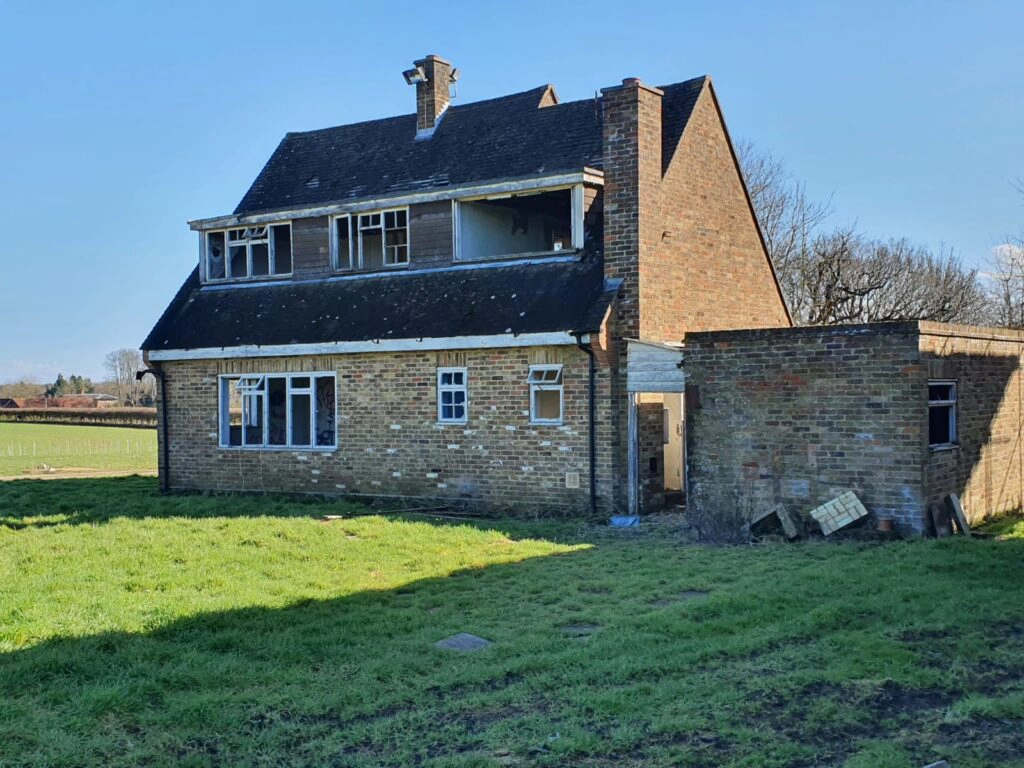 a large brick building with a grassy field with Olson House in the background